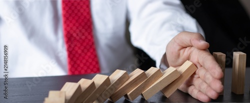 Cuadro en lienzo Hand halts falling dominoes