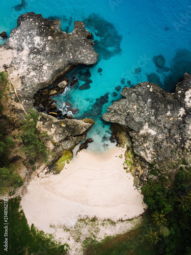 Secluded sandy cove flanked by dramatic coral rock formations at Pantai Mandorak in Sumba, Indonesia