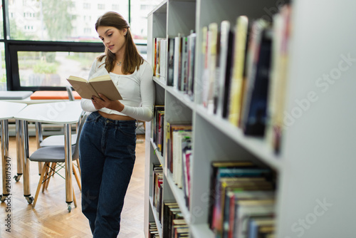 Foto Teenage girl immersed in a book at a modern school library