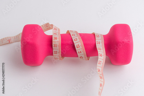 Pink dumbbells wrapped with measuring tape isolated on white background