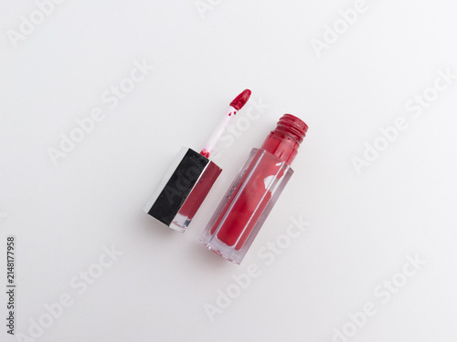 Red liquid lipstick and applicator wand flat lay isolated on a clean white background