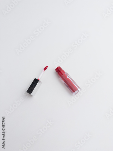 Red liquid lipstick and applicator wand flat lay isolated on a clean white background