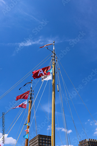Canvas Print Wooden sailboat masts decorated with colorful nautical flags under a clear blue