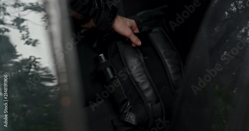 Man taking black travel backpack from car back seat with audio included