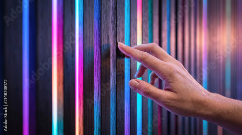 Human Hand Touching Illuminated Vertical Slatted Wall in Modern Luxury Interior