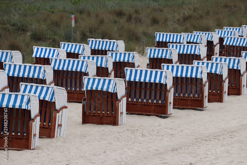 Rows of Strandkorb, a traditional German hooded windbreak seating furniture with blue-and-white-striped sun awning at the beach (Göhren, Baltic Sea, Germany)