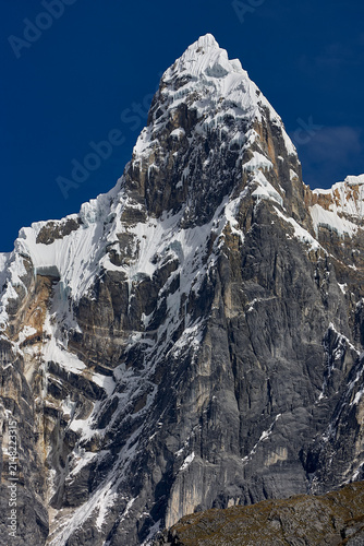 southeast face of Jirishanca reveals its full, imposing grandeur in Peru's Cordillera Huayhuash. Sheer walls of rock and ice rise in near-vertical lines toward a serrated summit, sculpted by centuries
