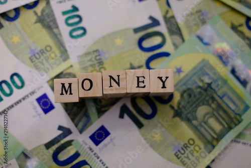 Wooden letters forming MONEY word on 100 euro banknote background, finance concept. Wooden alphabet letters forming money word on euro bills
