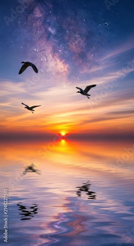 Three birds flying over a calm lake during a vibrant sunset with a visible milky way galaxy in the starry night sky above