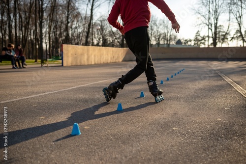 Konstfotografi Young man in a red hoodie practicing freestyle rollerblading tricks