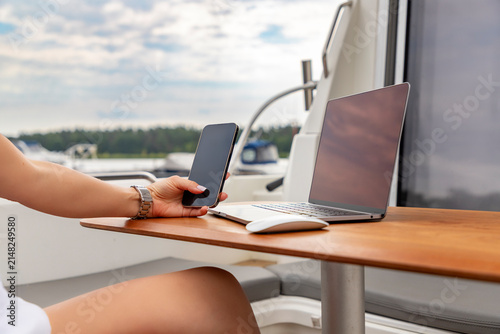 Woman Working on Laptop and Smartphone on Yacht. remote work