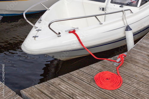 White Boat Bow Moored to Wooden Dock with Red Rope