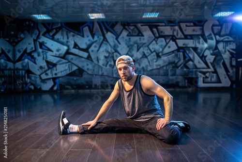 Obraz na płótnie Bearded breakdancer in baseball cap doing wide leg stretch