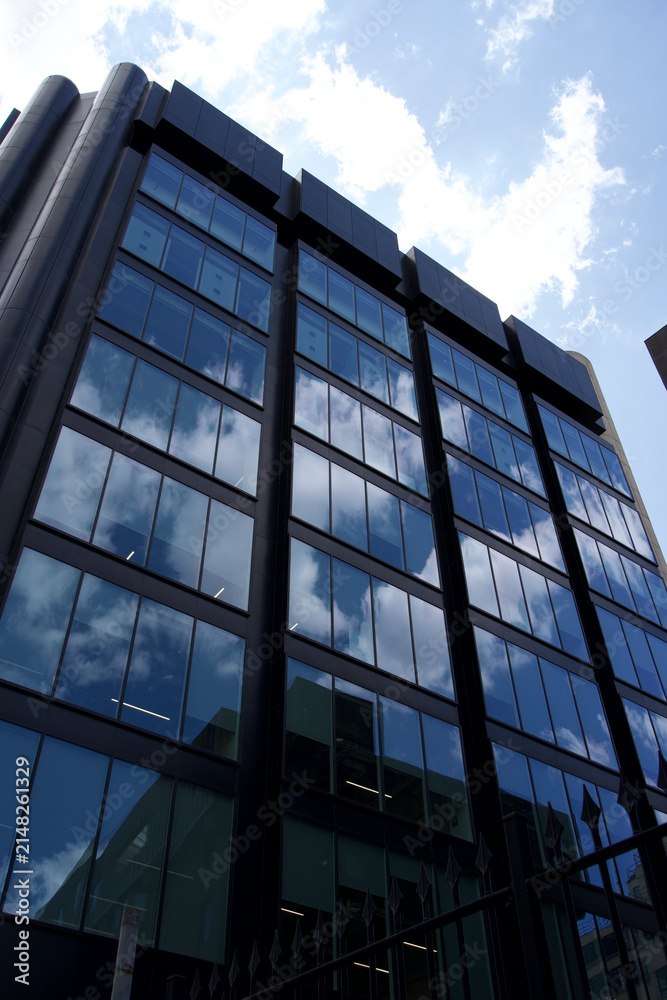 Obraz premium Tall Modern Glass Building Reflecting Sky and Clouds – Building, Modern, Architecture, Glass, Reflection, Sky, Cloud, Urban, Structure, Design, Contemporary 