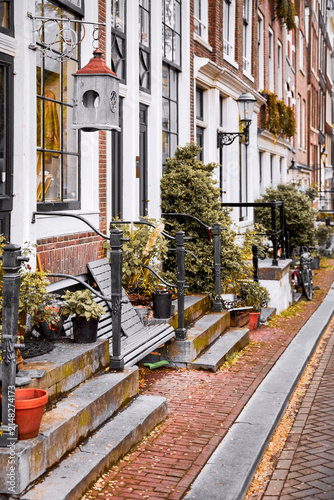 Amsterdam, Netherlands. Autumn street with traditional houses. Flowers in flowerpots, house entrance decoration with natural plants and flowers. Urban landscape.
