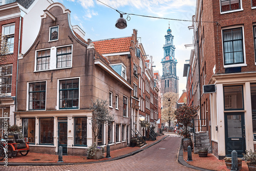 Amsterdam, Netherlands. Street view to the Mint Tower (Munttoren) on Muntplein square. Cosy street crossroads. Autumn evening sunny day with blue sky with clouds.