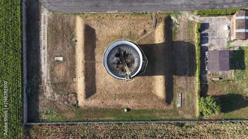 Aerial view of a circular industrial structure surrounded by dry grass and farmland in Chivasso, Piedmont, Italy.