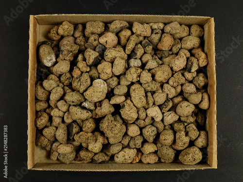 Heap of the  drainage materials, clay balls in a cardboard box , top view, on a black background