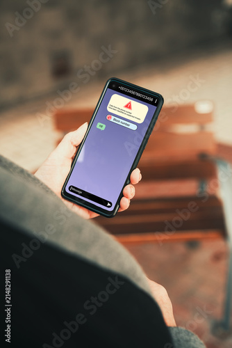 Woman holding smartphone with suspected scam call warning and block number option. Phone scams, cybersecurity, spam protection, and online safety awareness.