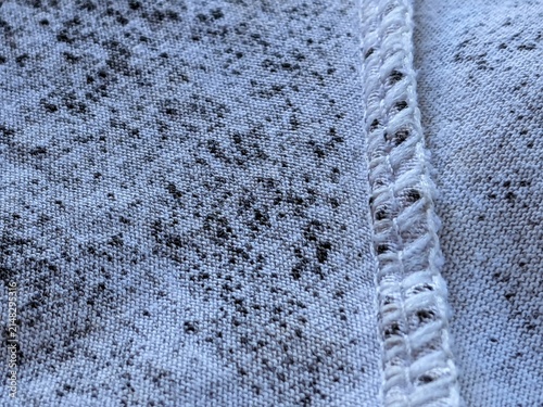 Obraz na plátne A close-up macro shot showing black fungal spots and mold growing on the texture of white knitted fabric, revealing damage caused by dirt and fungus