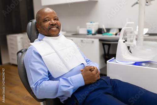 Smiling black male patient relaxing in comfortable dental chair during routine visit to a modern dental clinic, highlighting preventive care and patient comfort