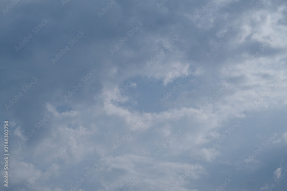 Obraz premium Gray layered clouds with a small blue opening, forming a soft daytime sky with shifting tones and gentle atmospheric texture.