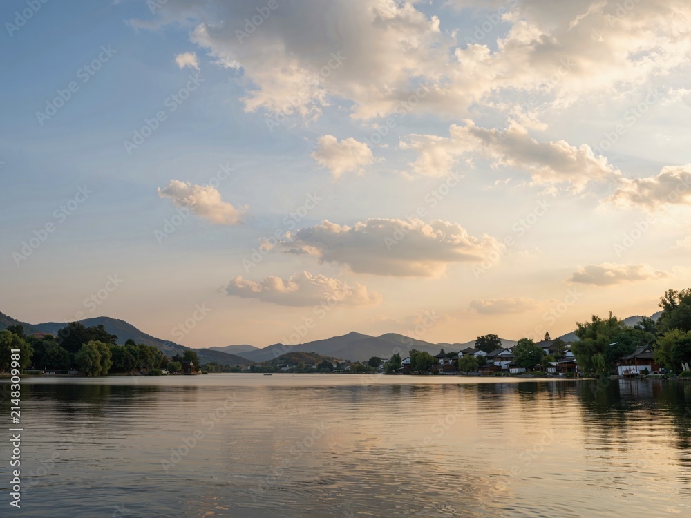 Obraz premium Sunset over a lake with mountains in the background