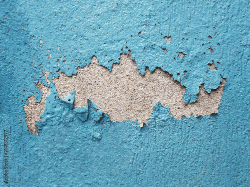 Peeling blue paint revealing rough concrete underneath. Concept of building decay, home maintenance, and weathered grunge texture background.