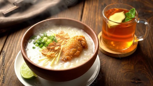 Bowl of rice porridge with fried chicken on a wooden table