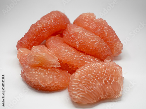 Healthy tropical pink pomelo fruit pulp segments isolated against a bright white background.