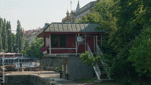 Smichov Lock control house stands along Vltava River in Prague, Czechia. Historic operator building with exterior stairs manages canal navigation. European waterway infrastructure scene.