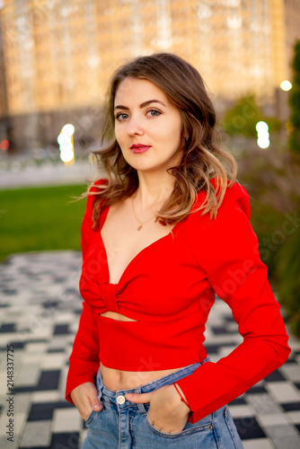 a beautiful young girl walking in the summer in a red sweater, a girl in the park in the summer, a portrait