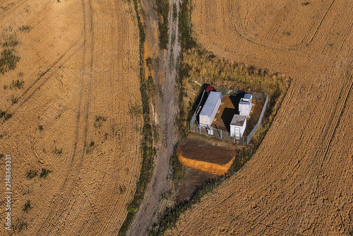Aerial view of a battery storage facility with containers and electrical equipment located in a dry agricultural field next to a dirt path in Randowtal, Brandenburg, Germany.