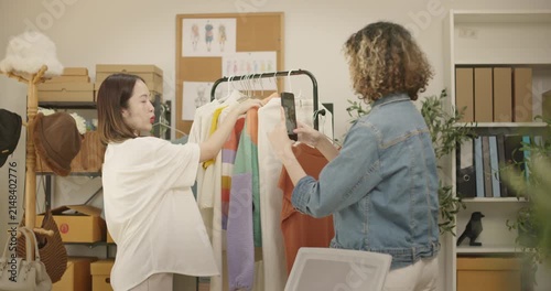 Asian woman influencer live streams a fashion product showcase from studio. Two female SME Online store business owner selling clothes on social media. entrepreneur, e-commerce, side hustle concept.