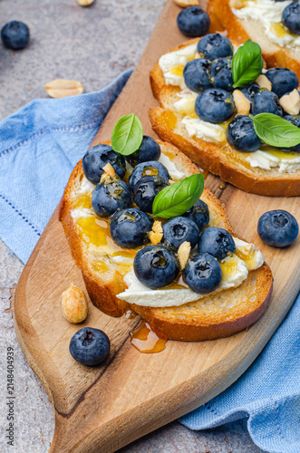 Blueberry, peanut, and cream cheese toasts on a wooden board
