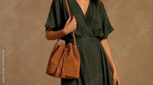 Stylish woman wearing a dark green dress with a tan leather bucket bag.