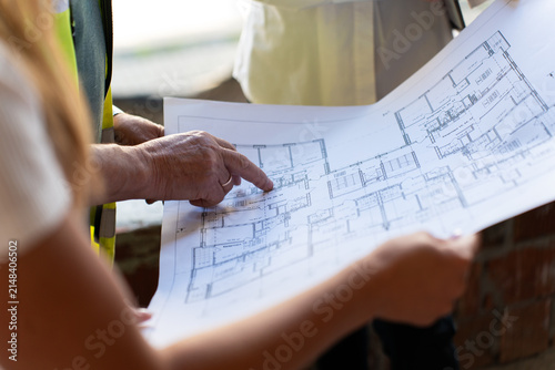 Workers study sketch of project observing proportions. Employees examine blueprint sketch interpreting symbols and notes marked by architect