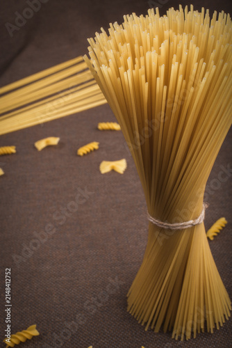 Cuadro en lienzo Two raw spaghetti bundles with farfalle pasta on dark background