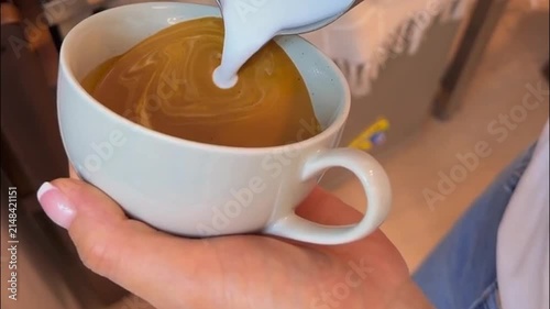 Barista Pouring Steamed Milk to Create Latte Art Rosetta Design in Coffee Cup