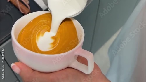 Barista Pouring Steamed Milk to Create Latte Art Rosetta Pattern in Coffee Cup