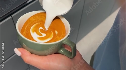 Barista Pouring Steamed Milk to Create Latte Art Rosetta Pattern in Green Coffee Cup