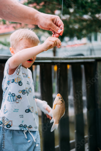 Child catches fish while fishing at a lake on a sunny day