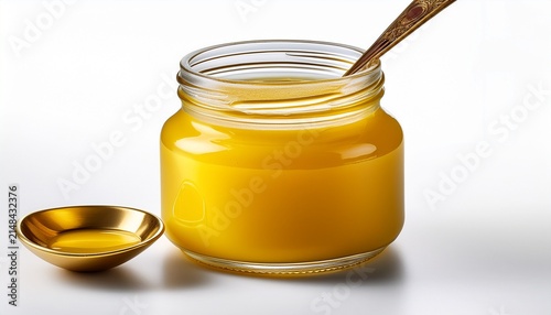 Jar Of Ghee With A Golden Spoon Resting Isolated On White Background