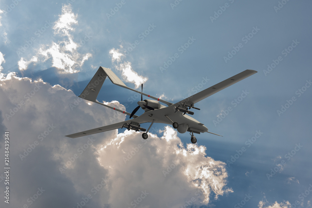 Obraz premium Military drone in flight with mounted munitions, optical equipment, propeller and extended landing gear against dramatic clouds.
