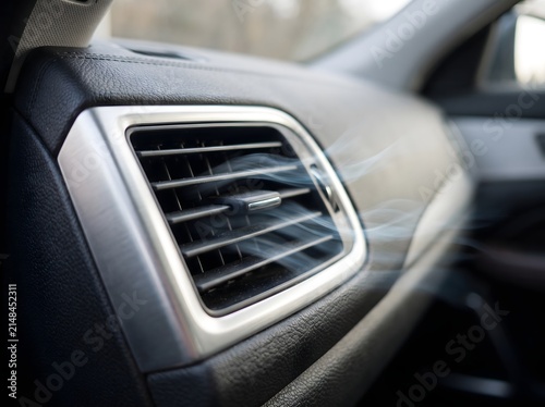 Close up of a modern car air conditioning vent blowing cool air into the vehicle interior cabin