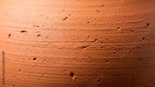 Rough textured terra cotta surface showing organic clay details with warm natural lighting and depth