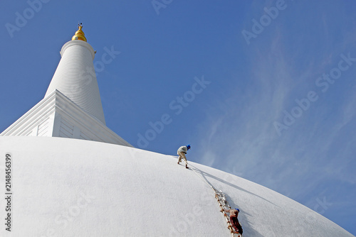Photography Workers Whitewashing Massive White Buddhist Stupa Dome under Blue Sky in Sri Lan