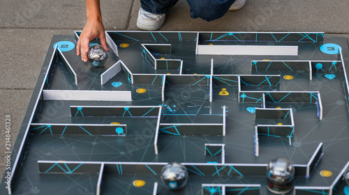 Child guides a programmable spherical robot through a maze during a beginner robotics workshop, exploring coding, technology and problem-solving through hands-on STEM education