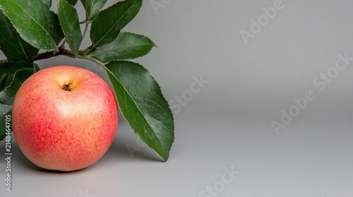 Fresh Red Apple with Green Leaves on a Gray Background.