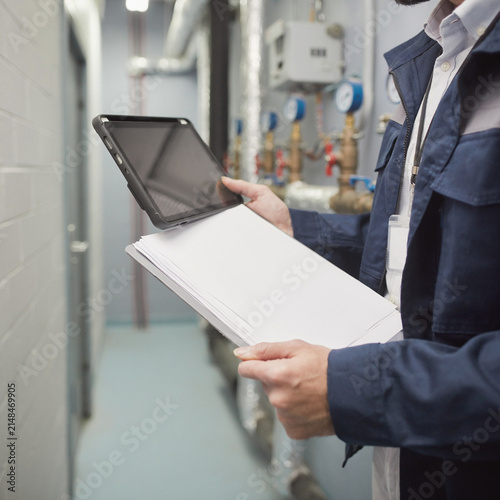 Technician using tablet during industrial equipment inspection